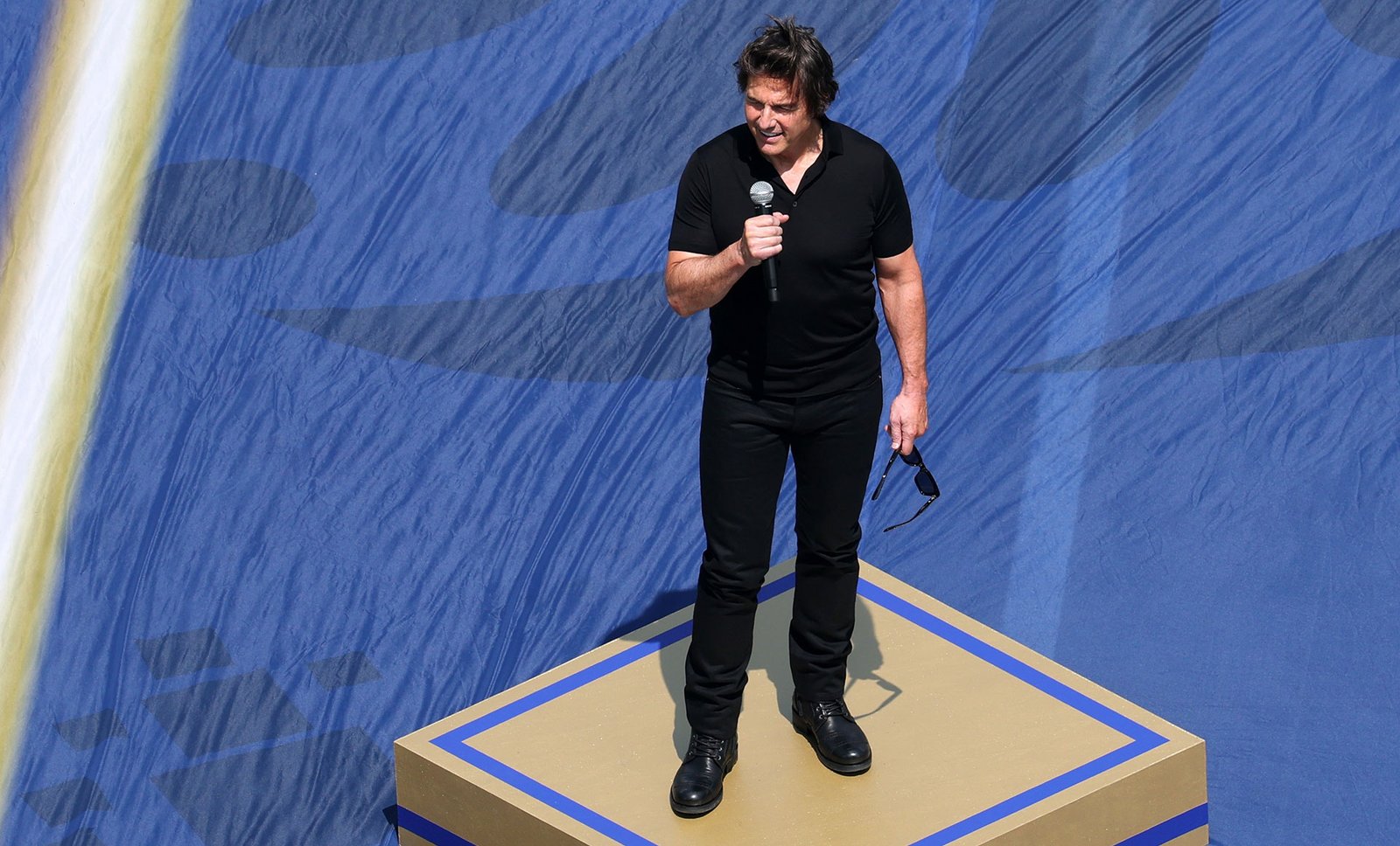 Tom Cruise con micrófono sobre un podio dorado durante el espectáculo previo a la final del Mundial 2026