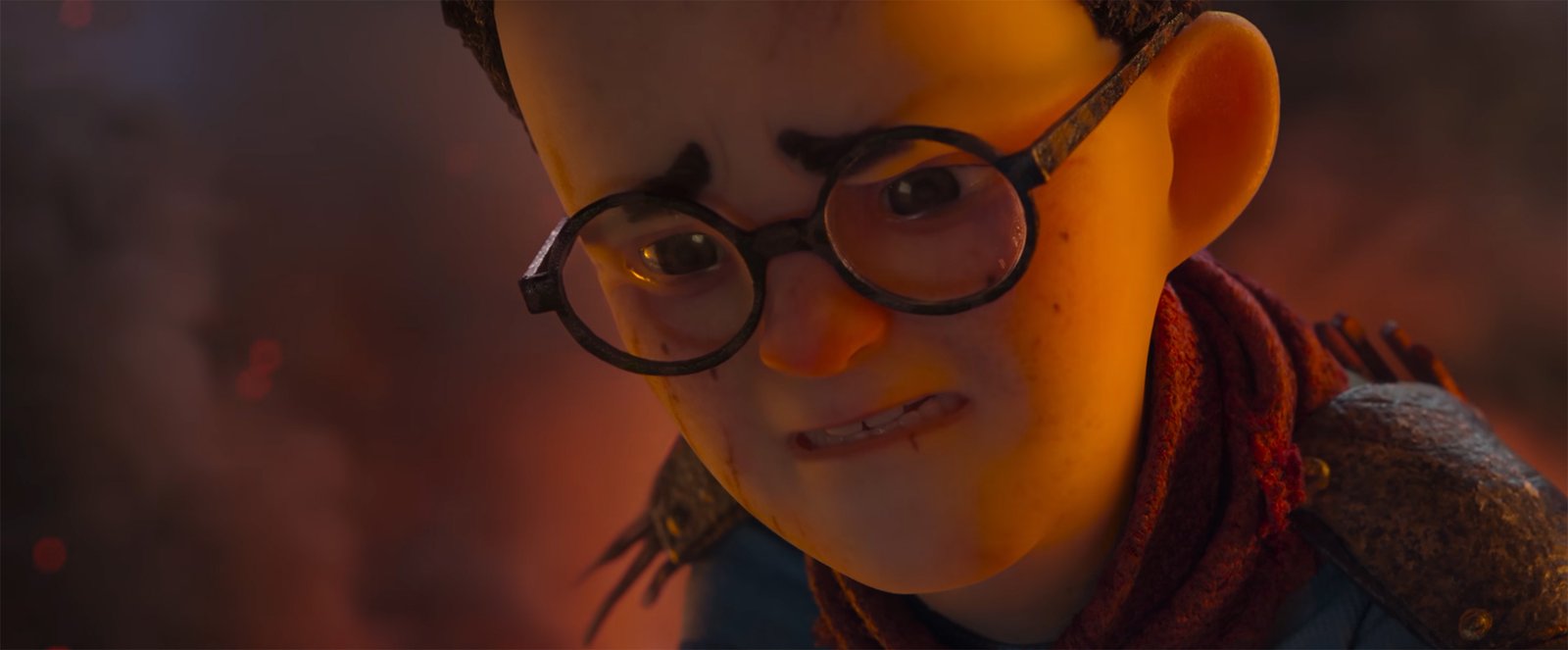 Primer plano de un niño con gafas redondas y bufanda roja, con el gesto crispado, ante un fondo de humo y brasas.
