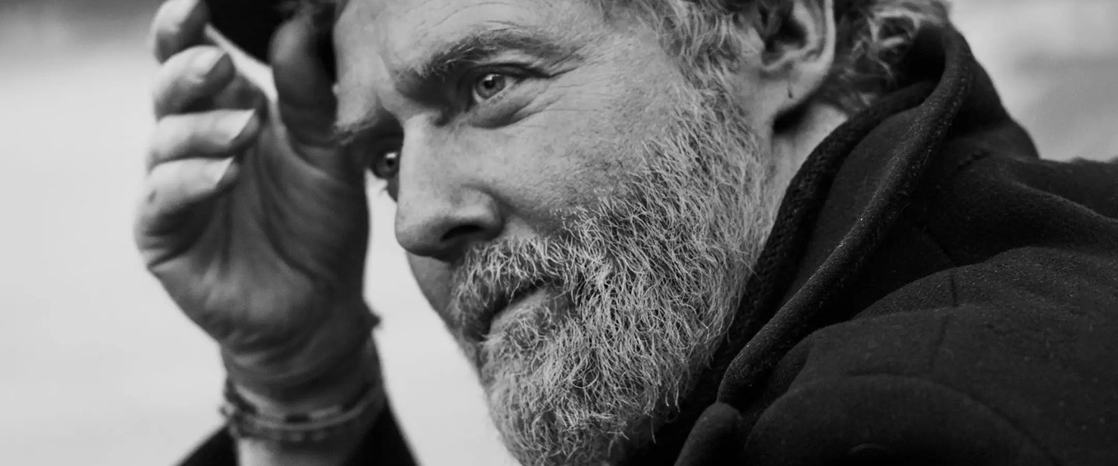 Primer plano en blanco y negro de Glen Hansard de perfil, con barba entrecana, llevándose la mano a la cabeza